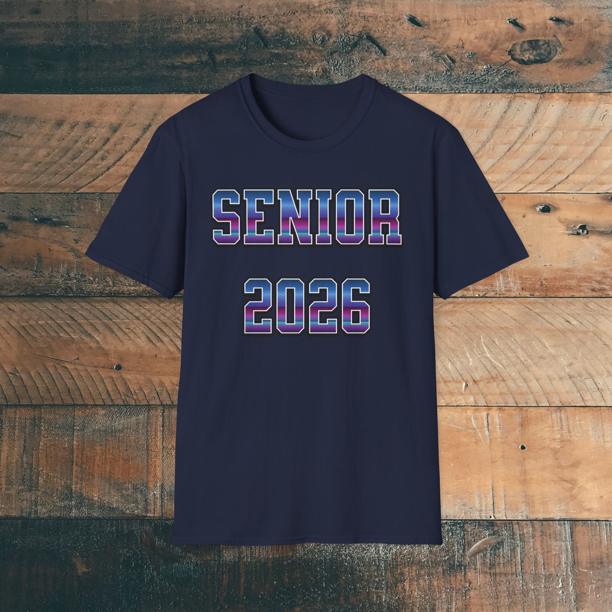 Navy blue t-shirt with 'SENIOR 2026' in purple and blue bold text on a wooden background. Brilliantmischief.shop