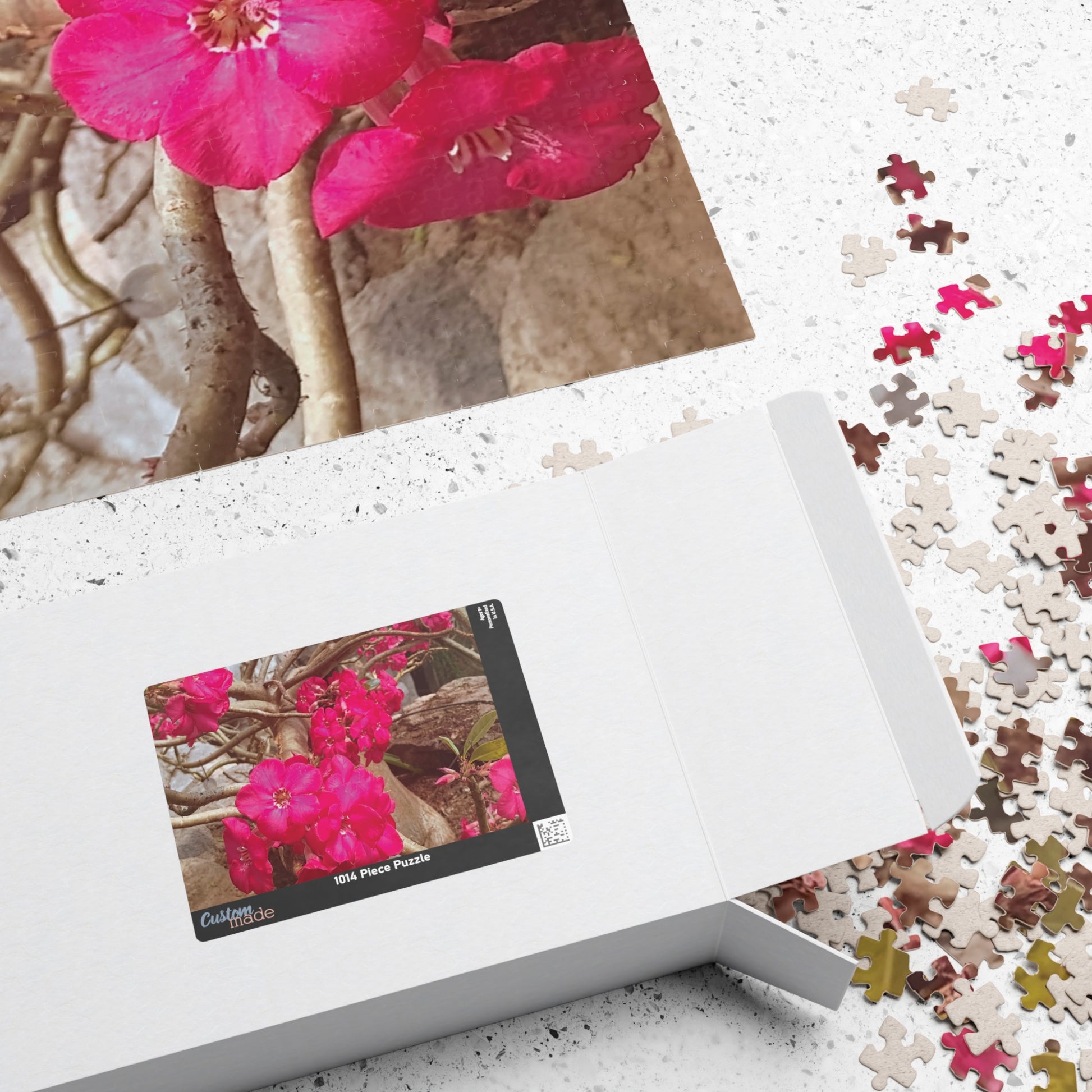 Jigsaw puzzle with pink flowers and a completed section on a white surface Brilliantmischief.shop